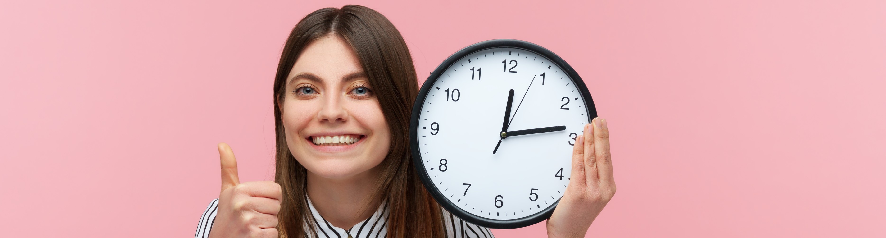lachende junge Frau mit sehr groß0er Uhr in der Hand 